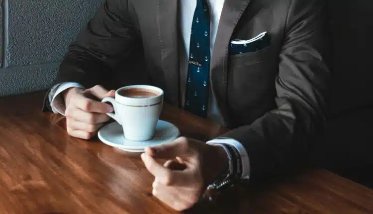 un homme en costard prenant un café